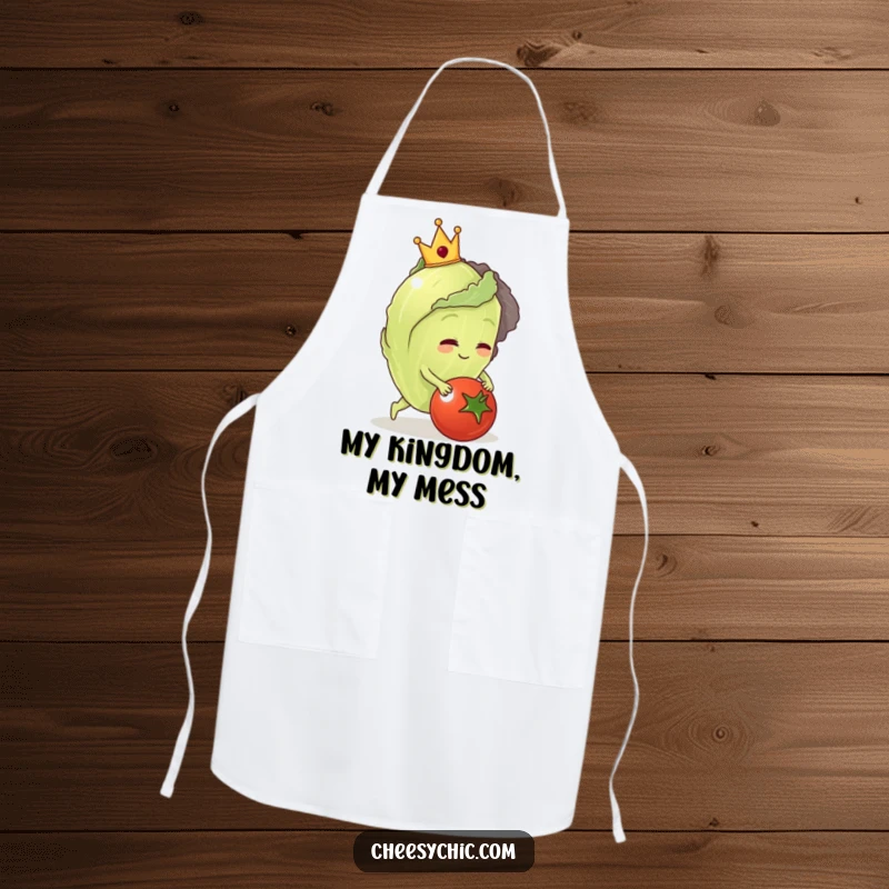 Funny apron featuring a regal lettuce wearing a crown, tripping over a tomato while cooking.