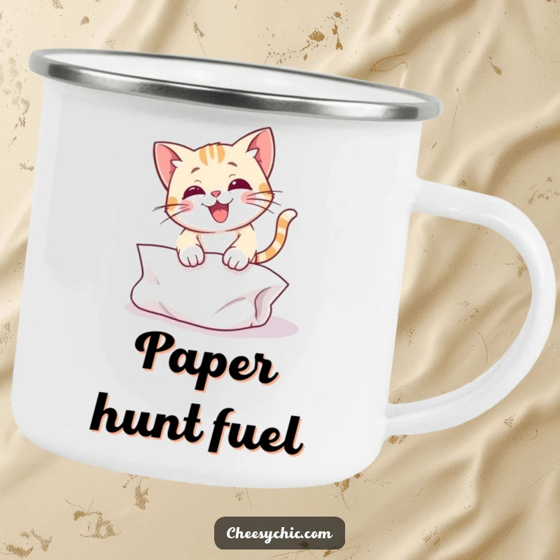 Funny camping mug illustrating a cute cat character mid-pounce, playfully attacking a crumpled piece of paper, ready for adventure.