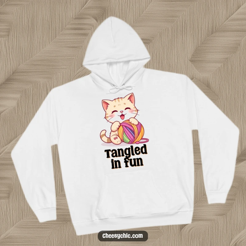 Funny hoodie depicting a cute cat character enthusiastically batting a large, colorful ball of yarn with joyful concentration.
